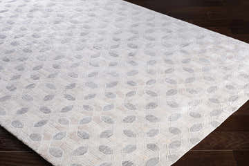 Close-up of the Belzoni Carpet, a cream and light slate hand-knotted rug with a contemporary geometric pattern. Corner