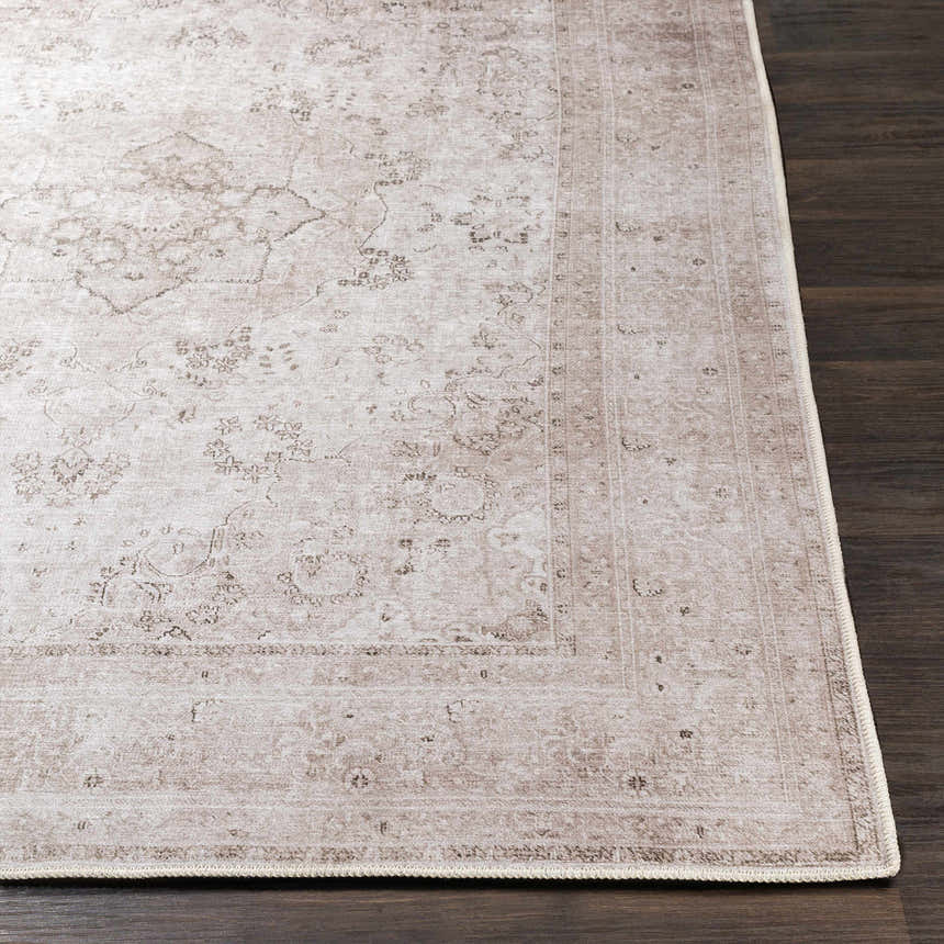 Close-up of the beige Bethany Vintage Flat Pile Washable Rug with a traditional floral pattern on dark wood flooring. Front