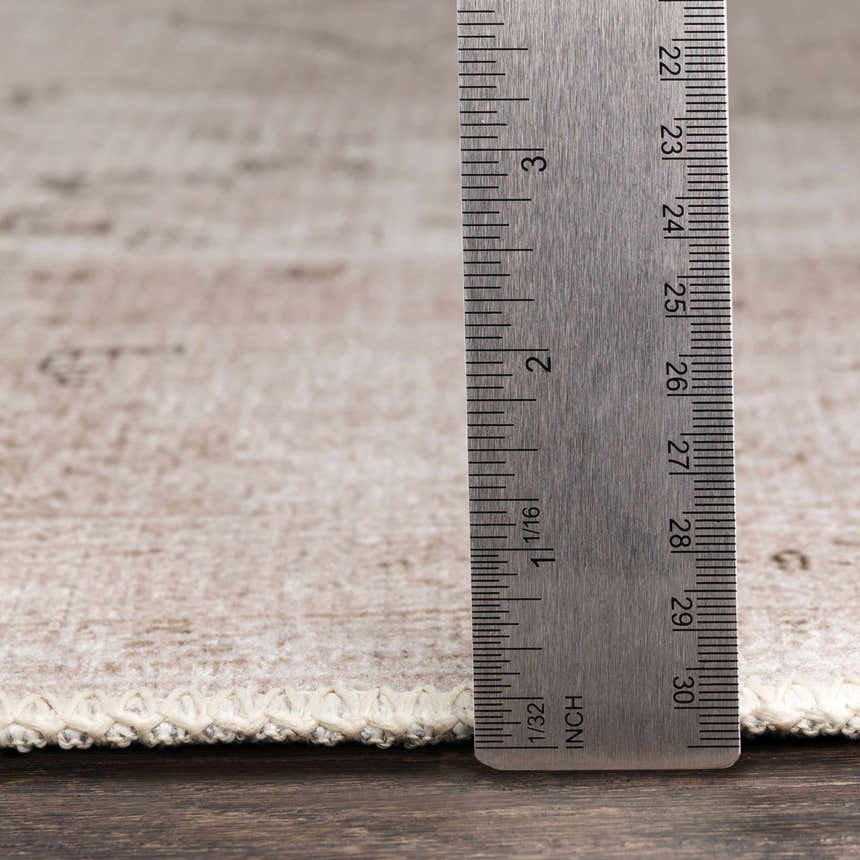 Close-up of the flat pile of the Beige Bethany Vintage Washable Rug with a ruler to show pile height. Pile