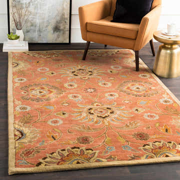 Living room scene with a Conesus 1112 rug, burnt orange chair, and gold side table. The rug has a floral pattern in beige, brown, and blue. Roomscene-Rectangle