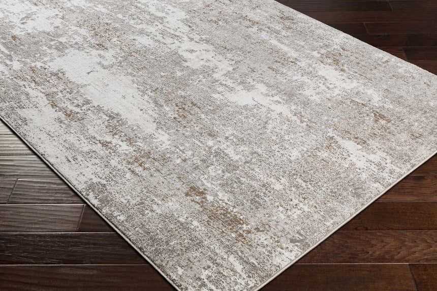 Close-up of the Binabaan Abstract Area Rug. Modern design with charcoal, gray, ivory, and tan tones. Machine woven texture. Corner
