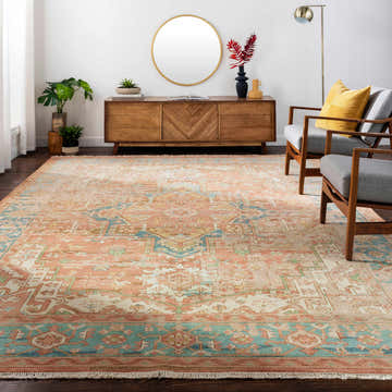 Living room scene with a brick red and blue Bangonay Area Rug, wood furniture, gray chairs, and a gold mirror. Roomscene-Rectangle
