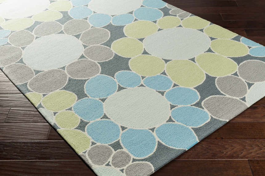 Close-up of the Bologna Area Rug with a contemporary circle pattern in blue, green, gray, and white on dark wood floors. Corner