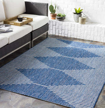 Outdoor patio scene with a Stephan Navy rug, white sofa, and brick wall. Roomscene-Rectangle