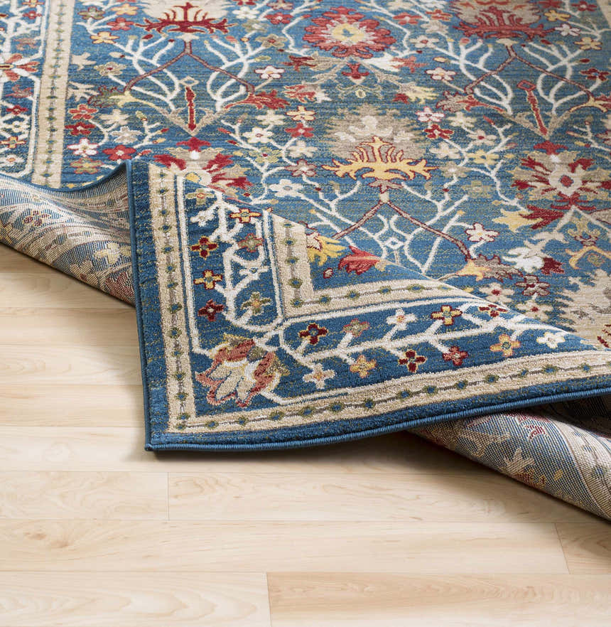 Close-up of the Neola Navy Blue Damask Area Rug, featuring a traditional floral pattern in red, yellow, and white on a blue background. Fold