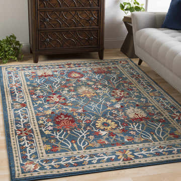 Living room scene with a Neola Navy Blue Damask Area Rug, wood dresser, and gray sofa. Floral pattern in red, yellow, and tan. Roomscene-Rectangle