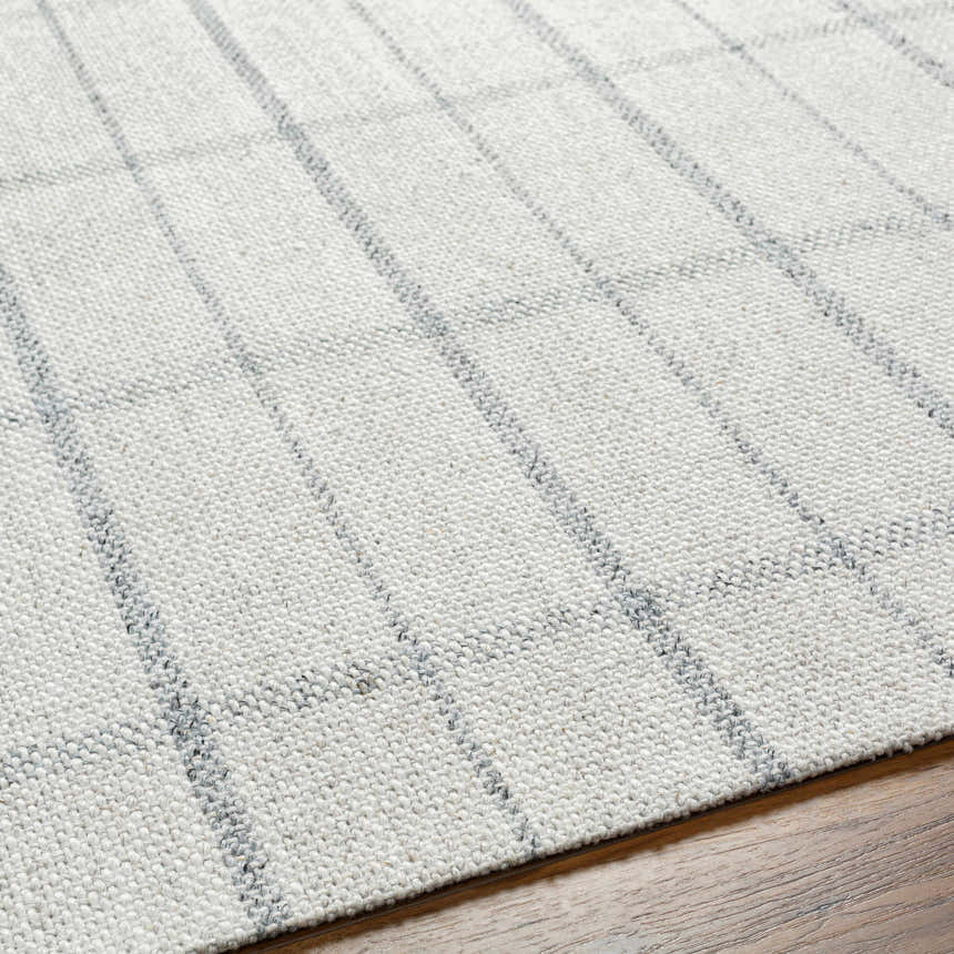 Close-up of the hand-woven Brava Area Rug. Gray and light gray wool and viscose blend with a simple grid pattern. Texture