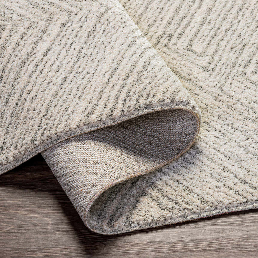Close-up of the Broadwater Luxe Rug showing its cream, light beige, and charcoal geometric pattern and soft texture. Fold