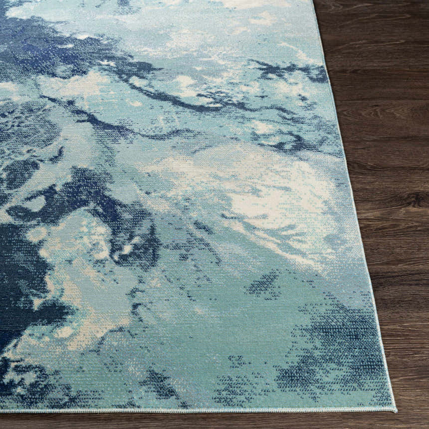 Close-up of Bright Sky Indoor/Outdoor Rug. Abstract design in ivory, light slate, navy, and pale blue on dark wood floor. Front