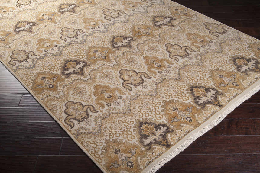 Close-up of the Brimson Area Rug, a hand-knotted wool rug with a traditional floral pattern in dark brown, tan, and off-white. Corner