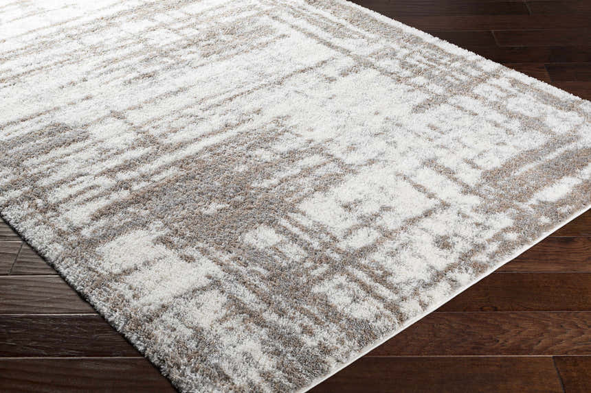 Close-up of the plush Broulee Abstract Striped Rug in cream, gray, and tan on dark wood flooring. Corner