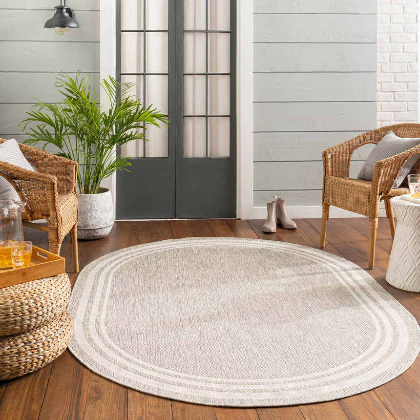Cozy porch scene with a beige oval Burradoo Bordered Area Rug, wicker chairs, and wood floors. Relaxing, neutral color palette. Roomscene-Oval
