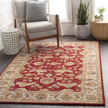 Living room scene with a red Brisbin Wool Area Rug, gray chair, and plants. Adds a traditional, cozy feel. Roomscene-Rectangle