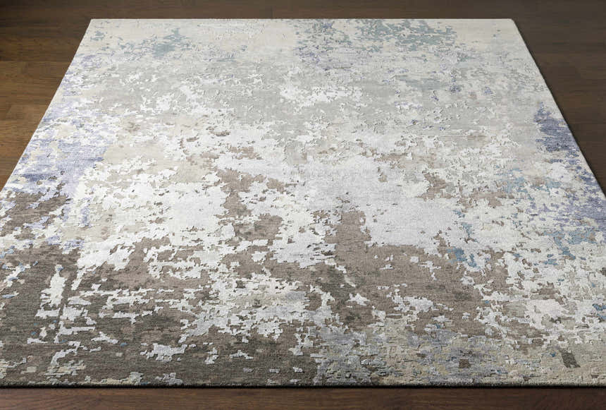 Close-up of the Bued Handmade Wool-Blend Rug. Abstract design in beige, brown, gray, ivory, and denim hues. Contemporary style. Front