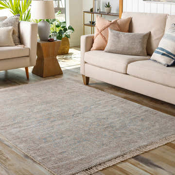Living room scene with Bunawan Premium Rug, beige sofa, armchair, wood floors, and natural light. Roomscene-Rectangle