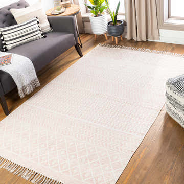 Living room scene with a light beige and rose Valyermo area rug, gray sofa, wood floors, and potted plants. Roomscene-Rectangle