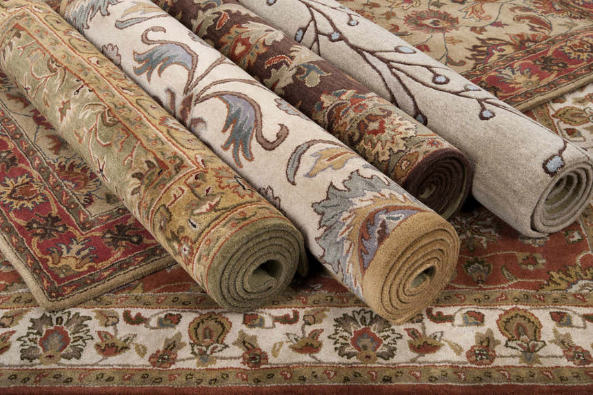 Rolled Alexander Brown Regency Wool Carpet samples showing beige, brown, and red traditional rug patterns. Styleshot