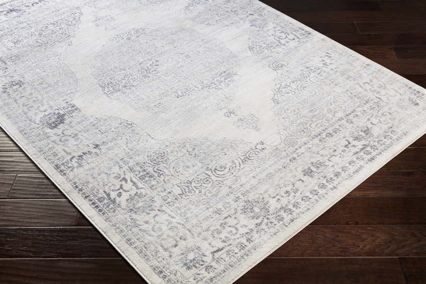 Close-up of a Caloundra Area Rug. Machine-woven polypropylene rug in charcoal, gray, and white with a traditional oriental pattern. Corner