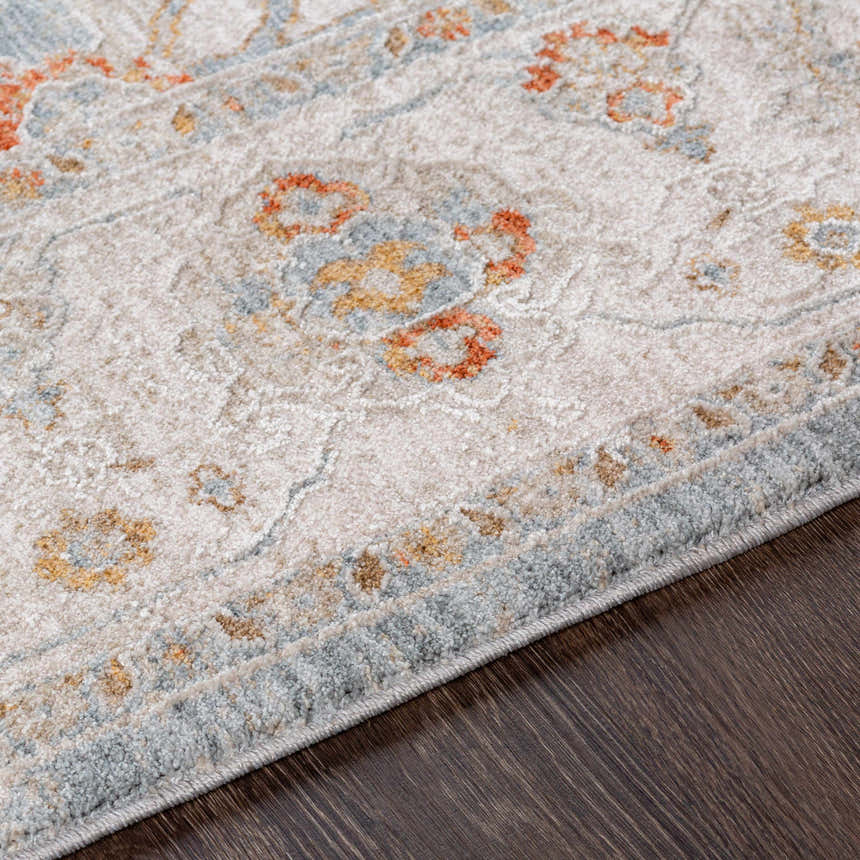 Close-up of the Camrose rug showing its light beige base with brick red, denim, and mustard floral accents. Texture