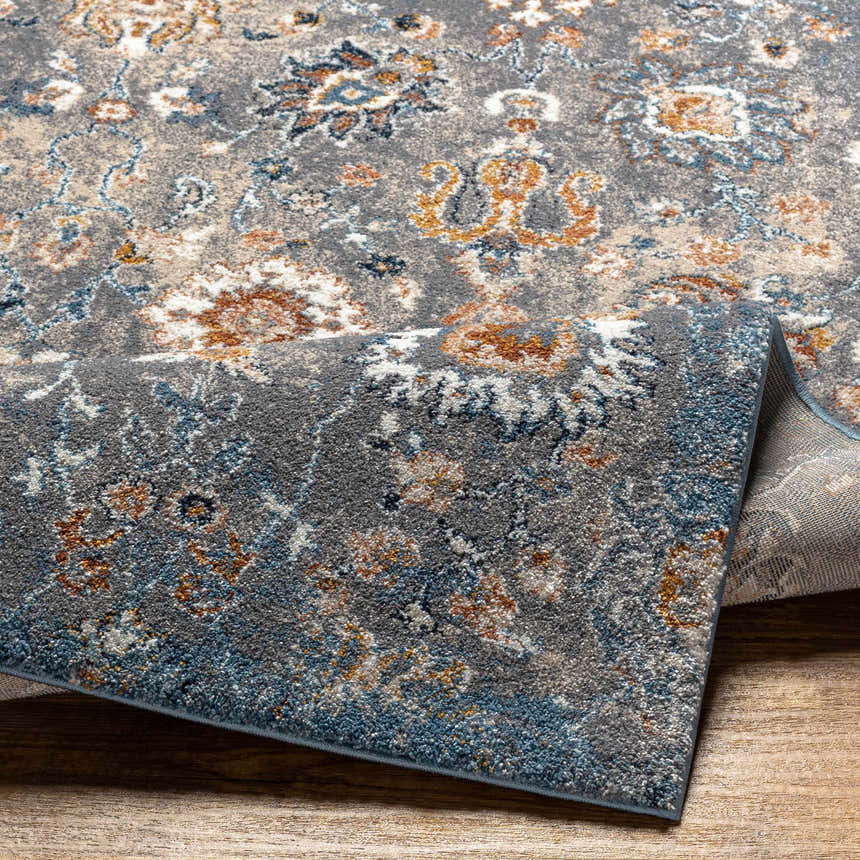 Close-up of the Cogan Gray Thick Rug showing its floral design, blue, brown, cream, and gray colors, and soft, textured pile. Fold