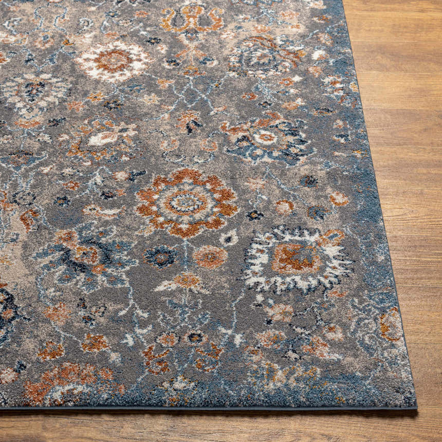 Close-up of the Cogan Gray Thick Rug showing its floral pattern in blue, brown, cream, and gray on a wood floor. Front