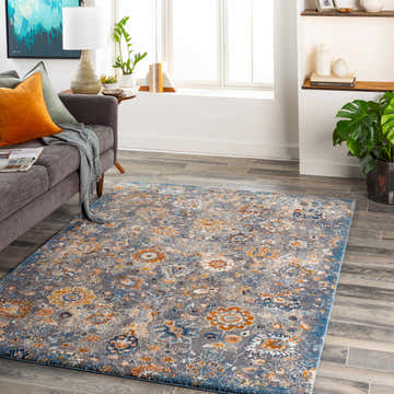 Living room scene with a gray sofa and the Cogan Gray Thick Rug, showcasing its blue, brown, and floral pattern. Roomscene-Rectangle