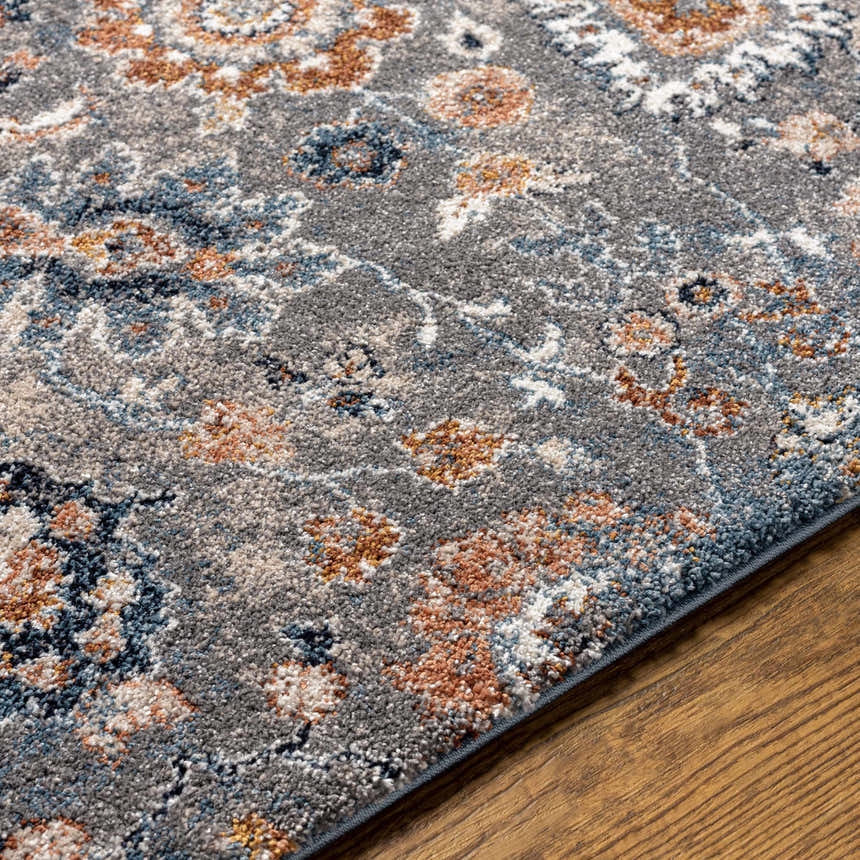 Close up of the Cogan Gray Thick Rug showing its floral pattern with blue, brown, and cream accents on a textured gray base. Texture