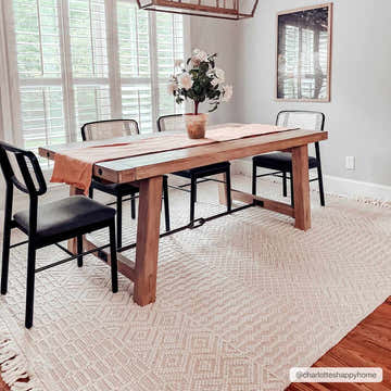 Dining room scene with a light peach Luyu Area Rug, wooden table, and black chairs. Roomscene-Rectangle