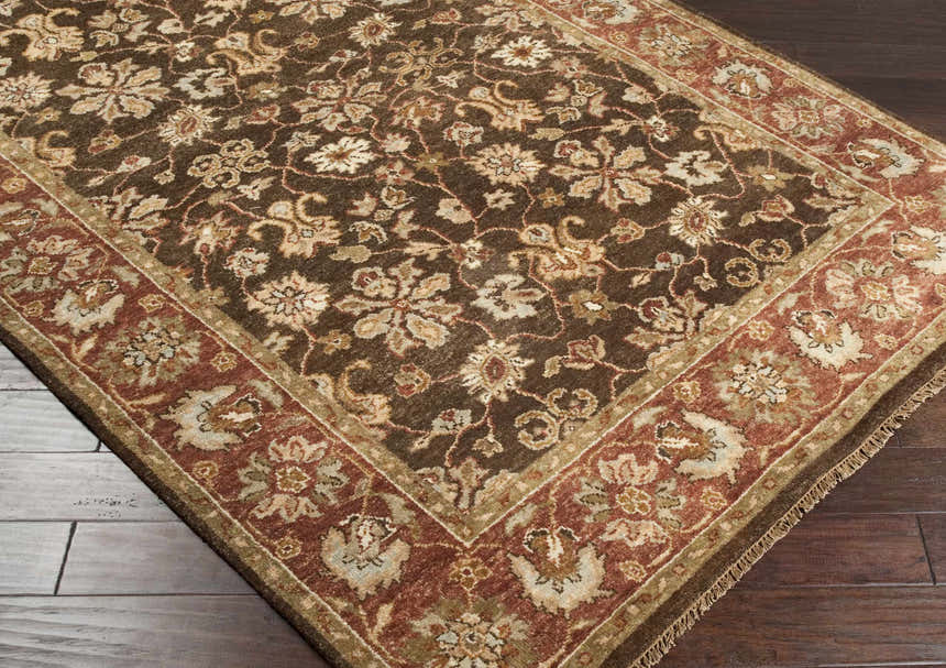 Close-up of the hand-knotted Chinle Premium Wool Area Carpet. Features a traditional floral pattern in brick red, brown, and beige tones. Corner