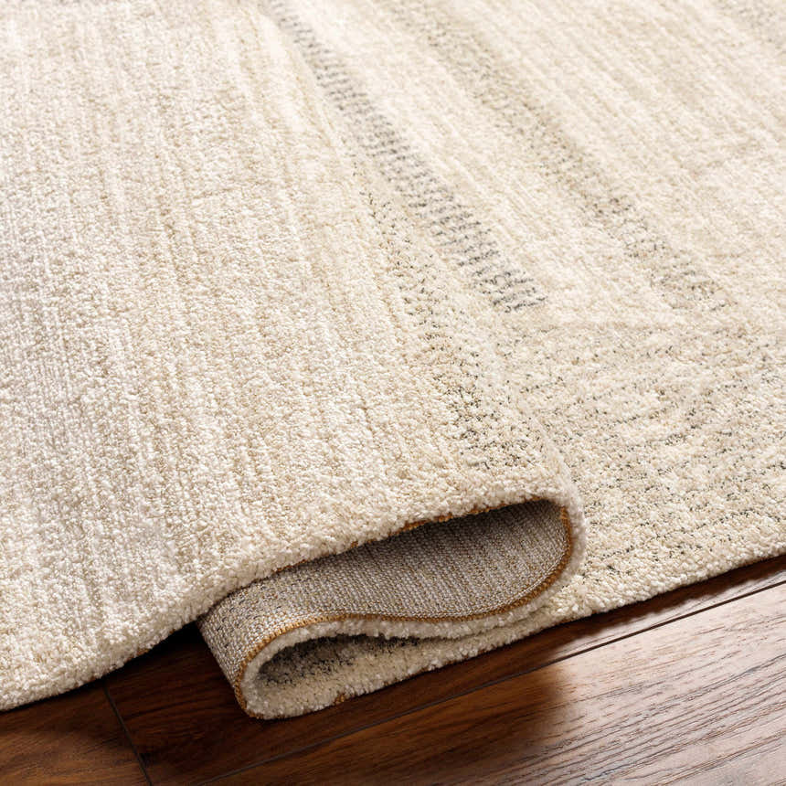 Close-up of the textured, bone-colored Chizu Geometric Luxe Rug with subtle gray stripes on dark wood flooring. Fold