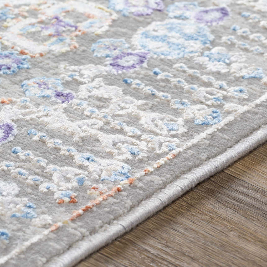Close-up of the Aisha Abstract Premium Sheen Viscose Rug. Features blue, purple, and peach floral accents on a gray background. Texture