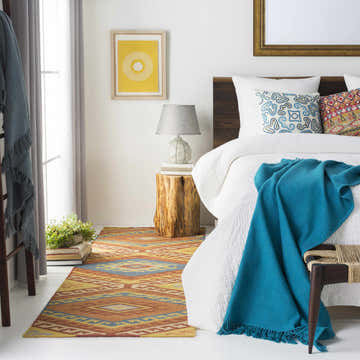 Bedroom scene with a Clutier Clearance Rug in beige, blue, and mustard colors adding warmth to the white floor. Roomscene-Rectangle