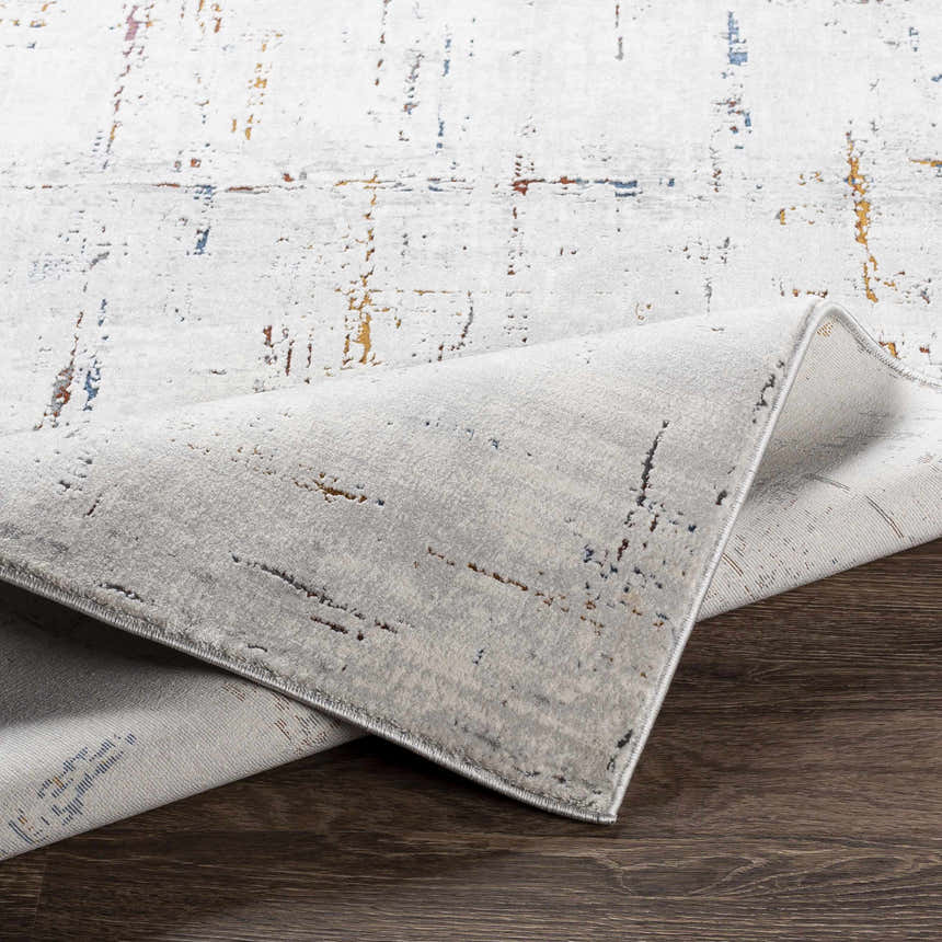 Close-up of the Concordia Faux Silk Rug showing its off-white base with burgundy, burnt orange, and blue abstract pattern. Fold