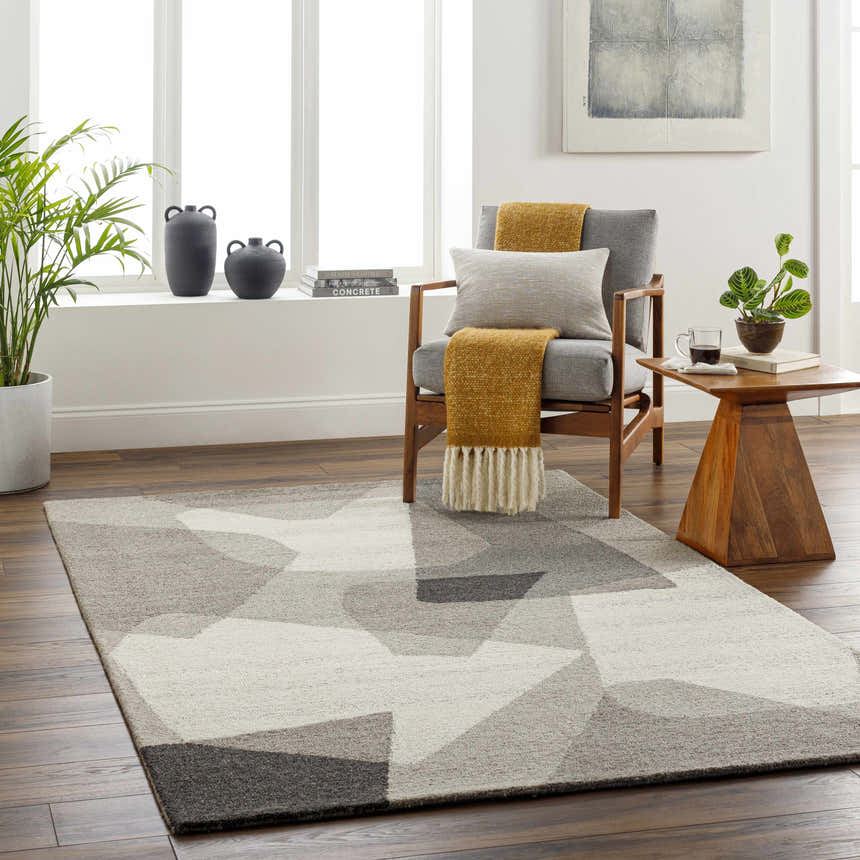 Living room scene with a geometric Colin Area Rug in beige, gray, and brown tones. Mid-century modern style with wood chair and side table. Roomscene-Rectangle