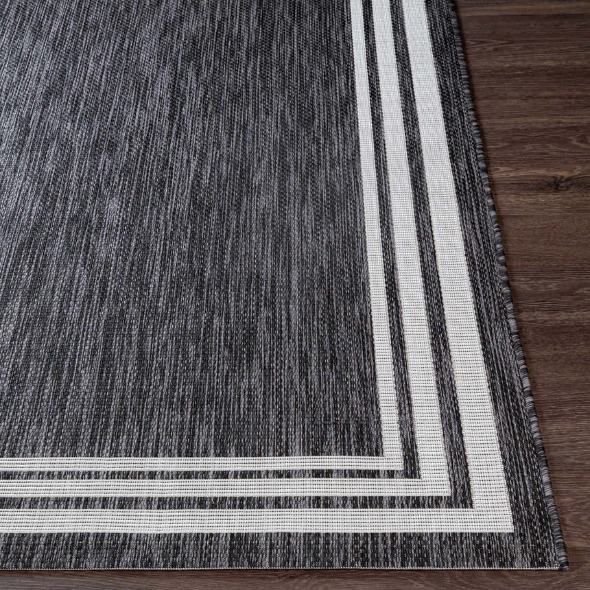 Close-up of the Coonamble Bordered Antrasit Rug. Charcoal rug with cream striped border on dark wood floor. Front
