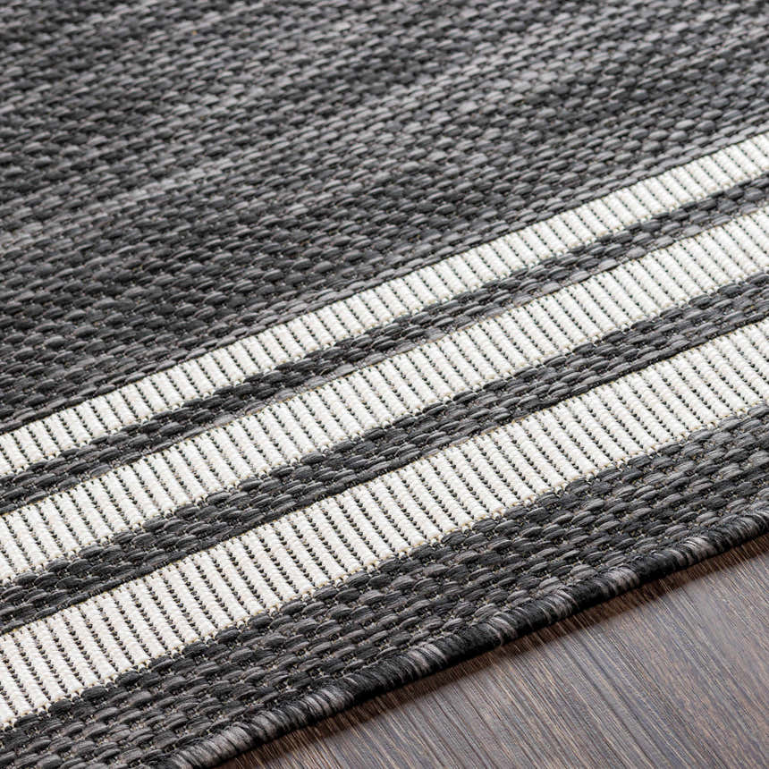 Close-up of the machine-woven Coonamble Bordered Antrasit Rug. Charcoal rug with cream striped border detail. Texture