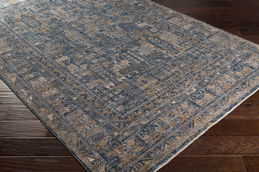 Close-up of the Mirabel Denim Blue Traditional Rug, showing its cream, blue, brown, and mustard intricate pattern and soft texture. Corner