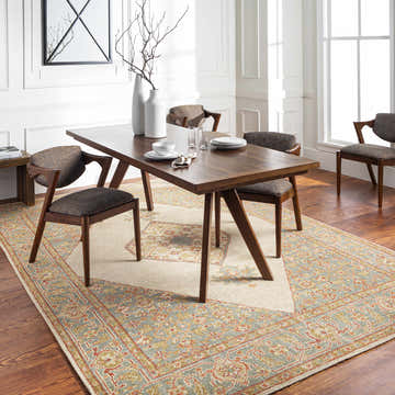 Dining room scene with a Coraki Area Rug in brick red, burnt orange, and dusty sage under a wood table and chairs. Roomscene-Rectangle