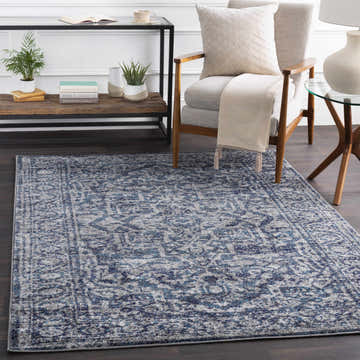 Living room scene with a Costigan Traditional Navy Rug, armchair, side tables, and dark wood floors. Roomscene-Rectangle
