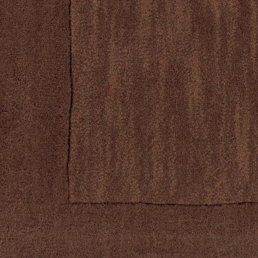 Close-up of the hand-loomed Bordered Solid Brown Wool Rug showing texture and dark brown color. Contemporary style. Swatch