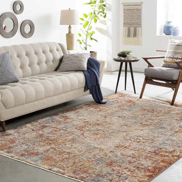Living room scene with a neutral sofa and the Cranfield Area Rug in brick red, cream, and blue tones. Roomscene-Rectangle