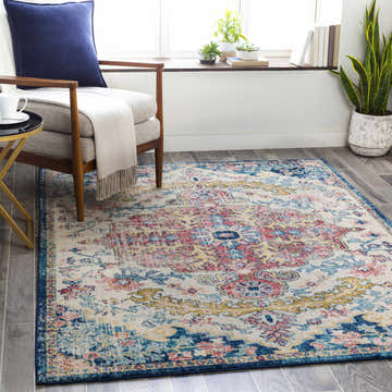 Living room scene with a Corrimal Area Rug in aqua, burgundy, and blue, styled with a chair, side table, and plants. Roomscene-Rectangle
