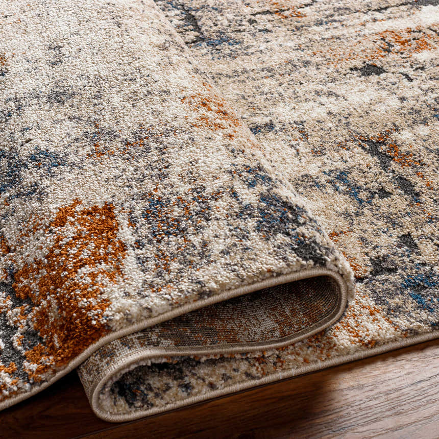 Close-up of the Cashi Thick Luxe Rug showing its clay, mocha, and off-white abstract pattern and plush texture. Fold