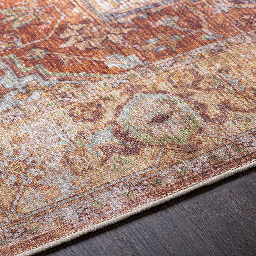 Close-up of the Casterton Washable Area Rug showing brown, orange, green, and beige traditional pattern and texture. Texture
