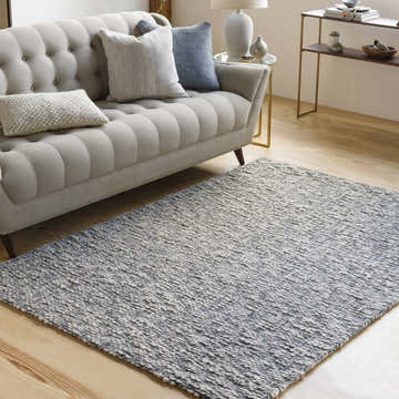 Living room scene with a Cushendall Premium Rug in dark blue and off-white under a tufted sofa. Contemporary style. Roomscene-Rectangle