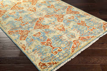 Close-up of Cutler Cream/Orange Wool Runner Rug with a traditional design on dark wood floors. Bohemian style. Corner