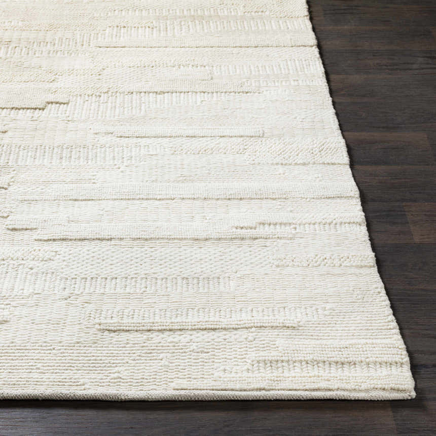 Close up of textured Cypress Cream Wool Rug on dark wood floor. Hand woven rug with natural fibers. Front
