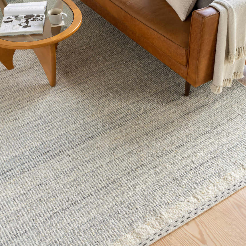 Living room scene with a brown leather couch and the Dalaoig Flat Woven Wool Rug in cream and charcoal. Roomscene-Rectangle