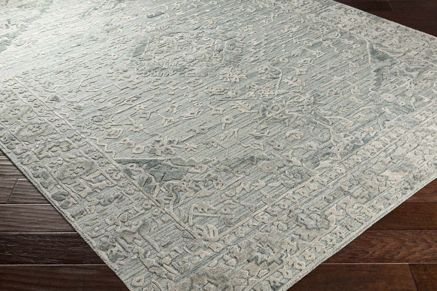 Close-up of the hand-loomed Davilla Area Rug. Light sage, seafoam, and light gray Persian-style pattern. Viscose texture. Corner