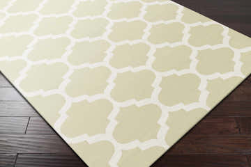 Close-up of the Dearborn Area Carpet Area Rug. Cream and light green quatrefoil pattern on a hand woven cotton rug. Corner